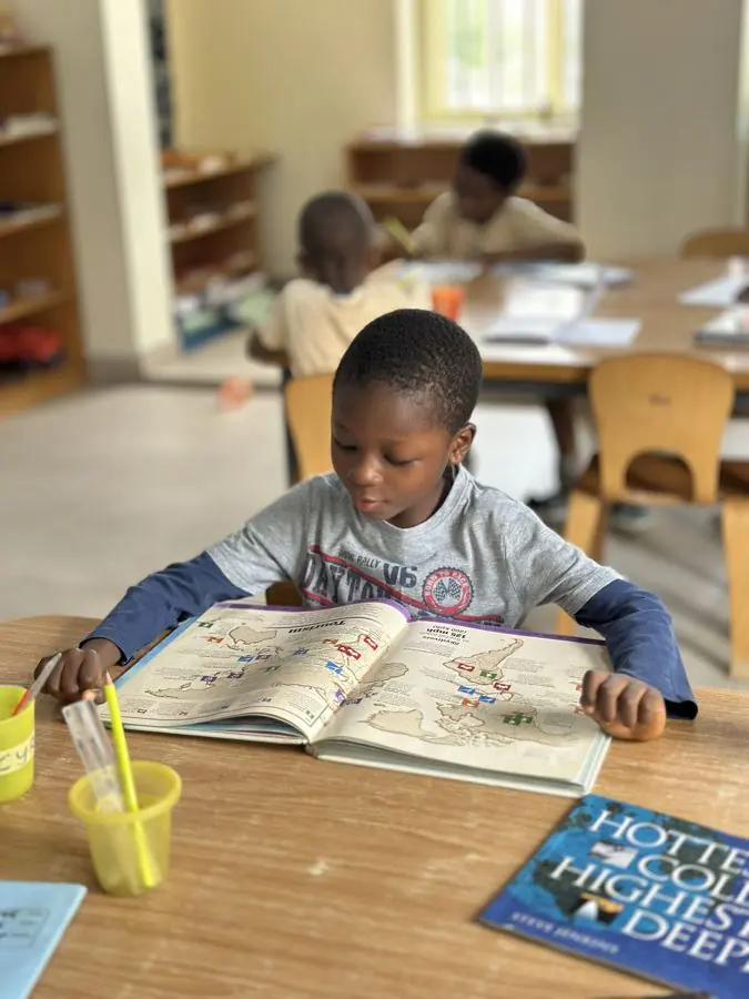 A boy reading a book at a classroom table