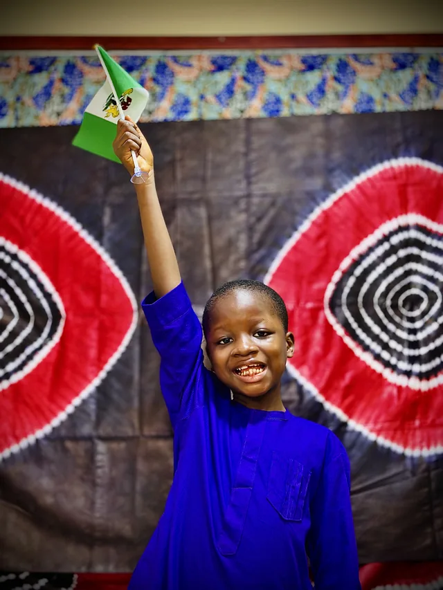 A child joyfully waving the Nigerian flag during the celebration