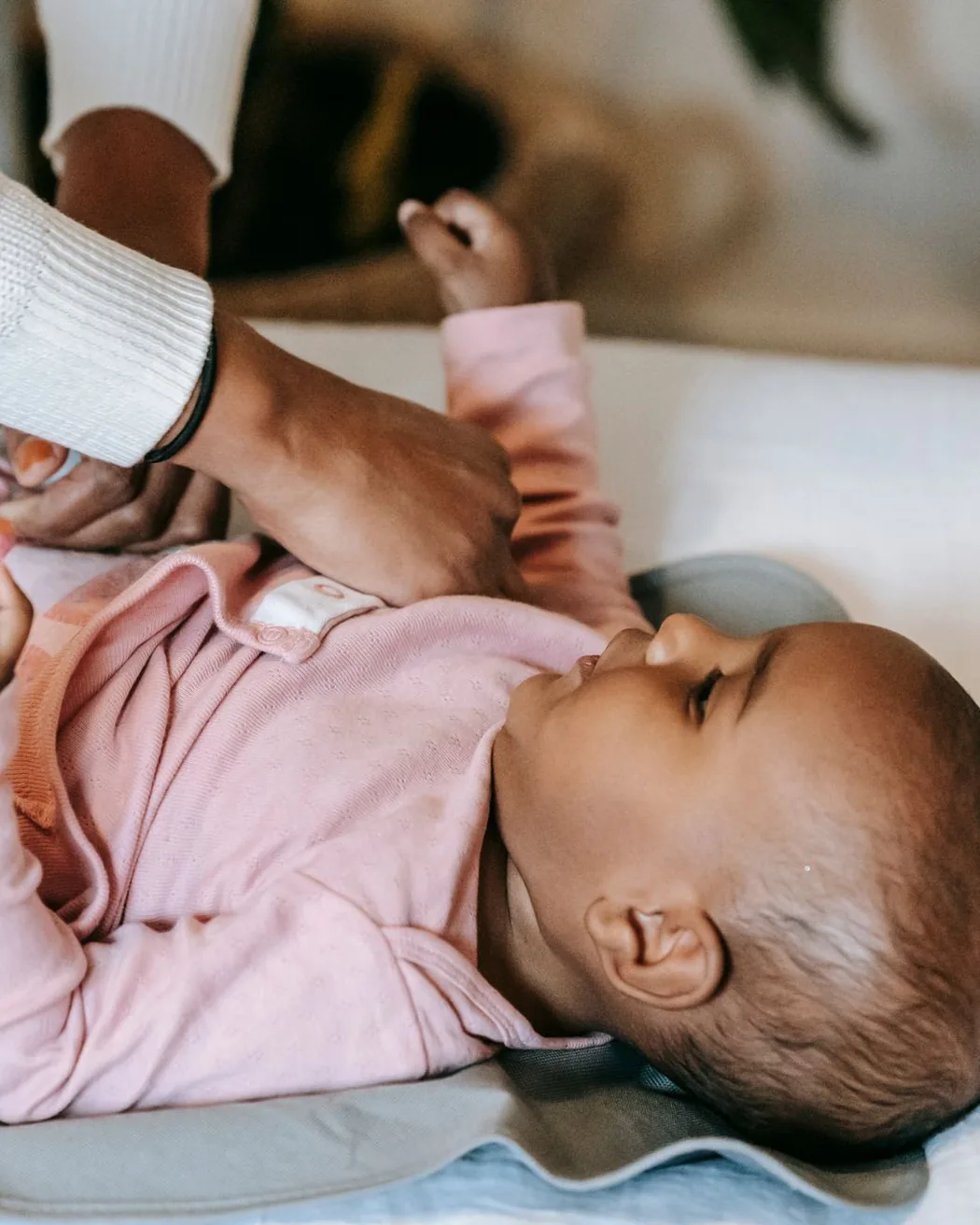 A parent gently dressing their baby