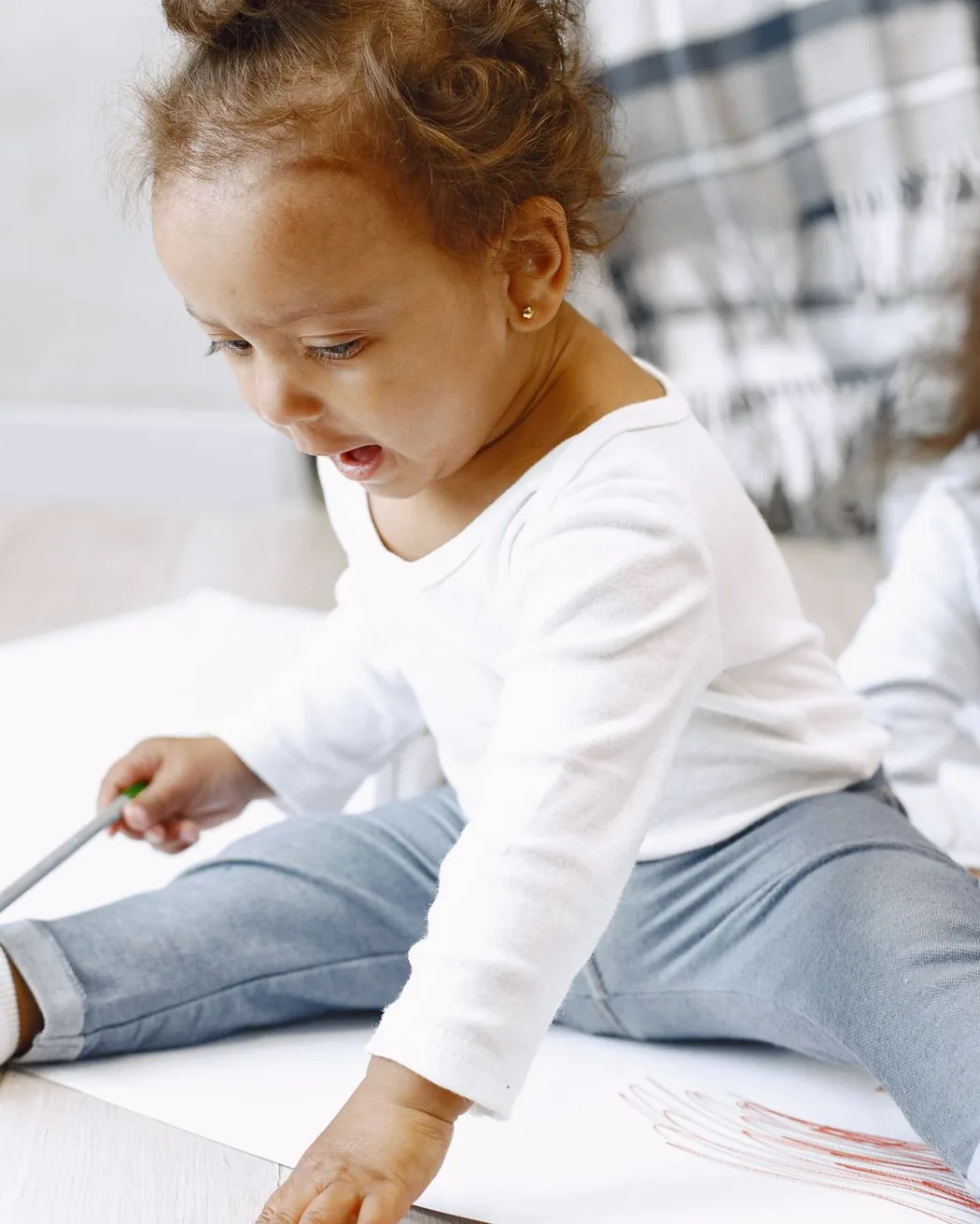 A young child at Aquila Nidus drawing with her older sister